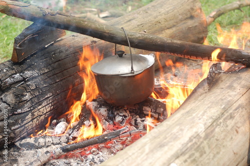 Cooking on an open fire in field conditions. Boiling water in the bowler on the bonfire. Close-up. The camp.  Cooking in the wild.