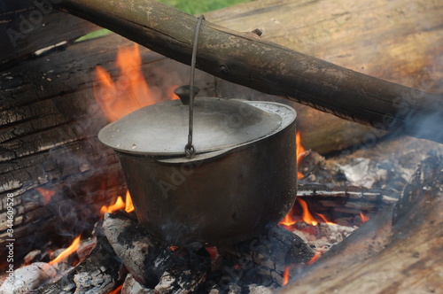 Cooking on an open fire in field conditions. Boiling water in the bowler on the bonfire. Close-up. The camp.  Cooking in the wild.