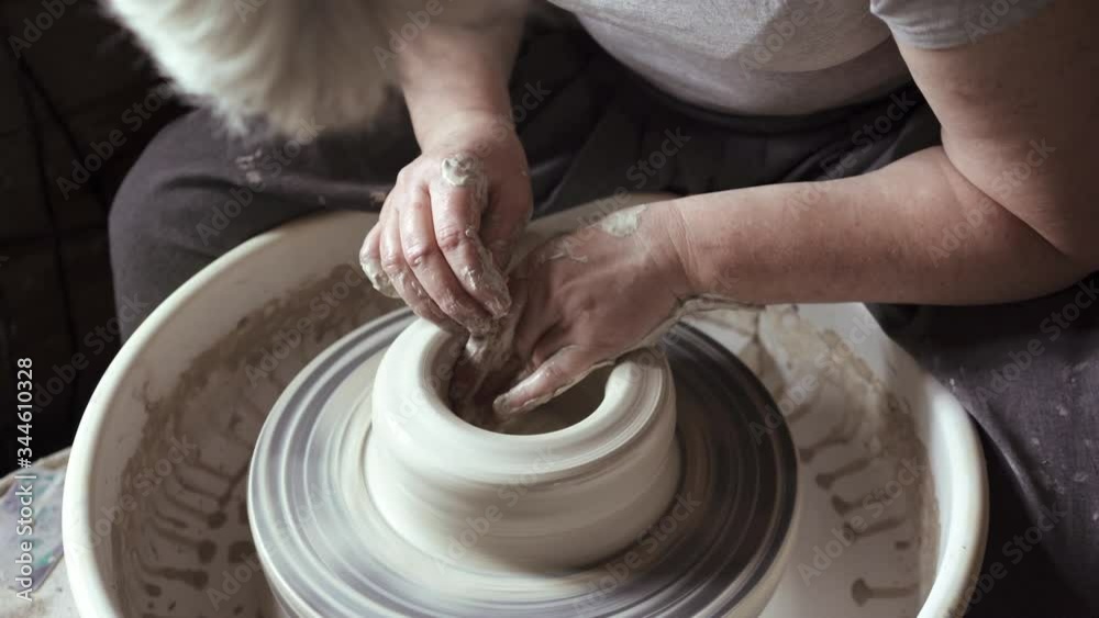 Female potter making a clay pot on a pottery wheel in a workshop Female potter making a clay pot on a pottery wheel in a workshop