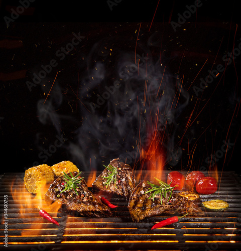 Tasty beef steaks on the grill with fire flames