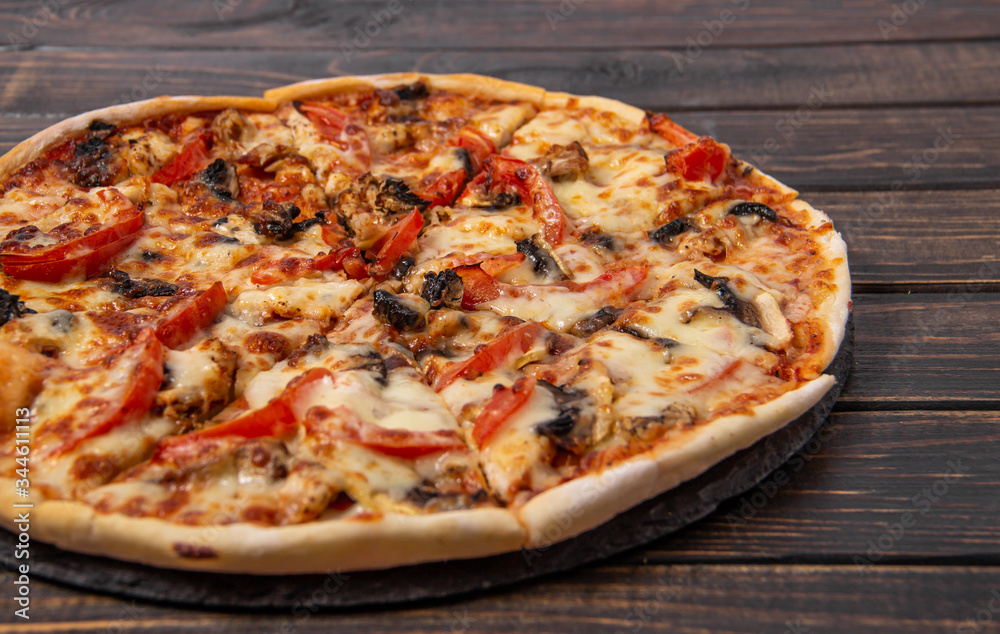 Pizza with mushrooms and chicken on a wooden table.