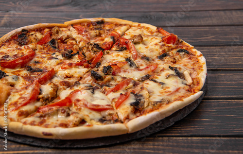 Pizza with mushrooms and chicken on a wooden table.