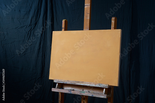 traditional oil Primed Linen stretched canvas panel painting support. Fresh GESSO priming. On an easel . Dark background isolated cool artist studio mockup photo