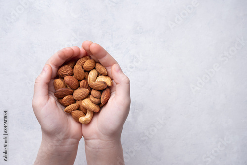 the child's hands hold a handful of nuts over a light gray background