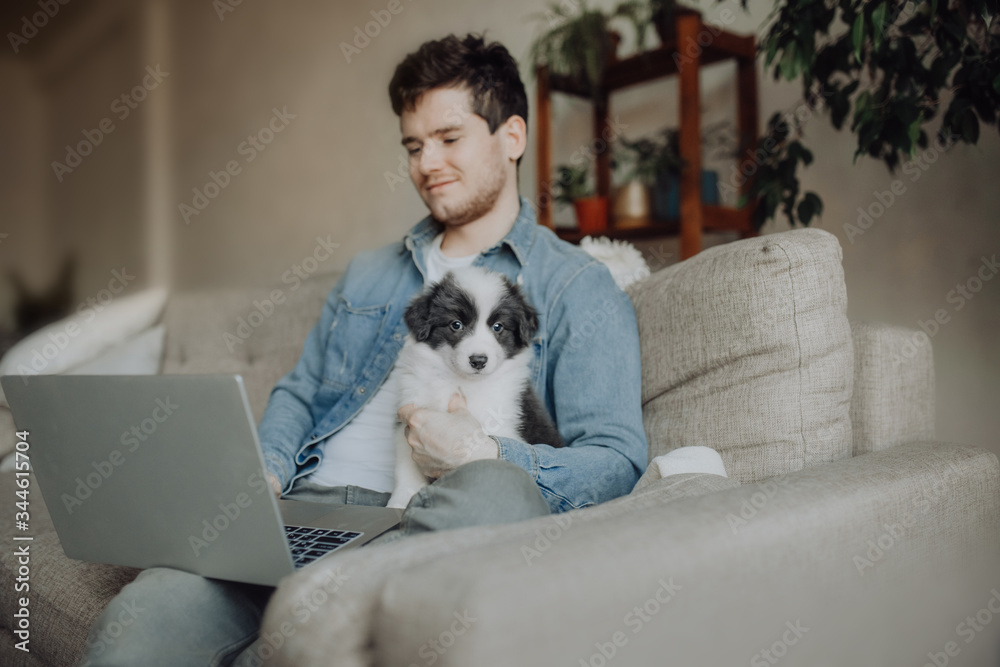 Handsome young men works on his laptop with his puppy at his side