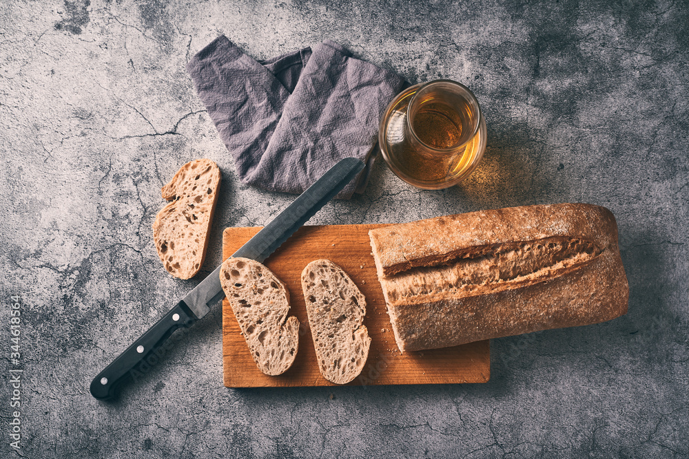 Homemade bread cut on a wooden board together with a bottle of extra virgin olive oil. Traditional Mediterranean breakfast concept.