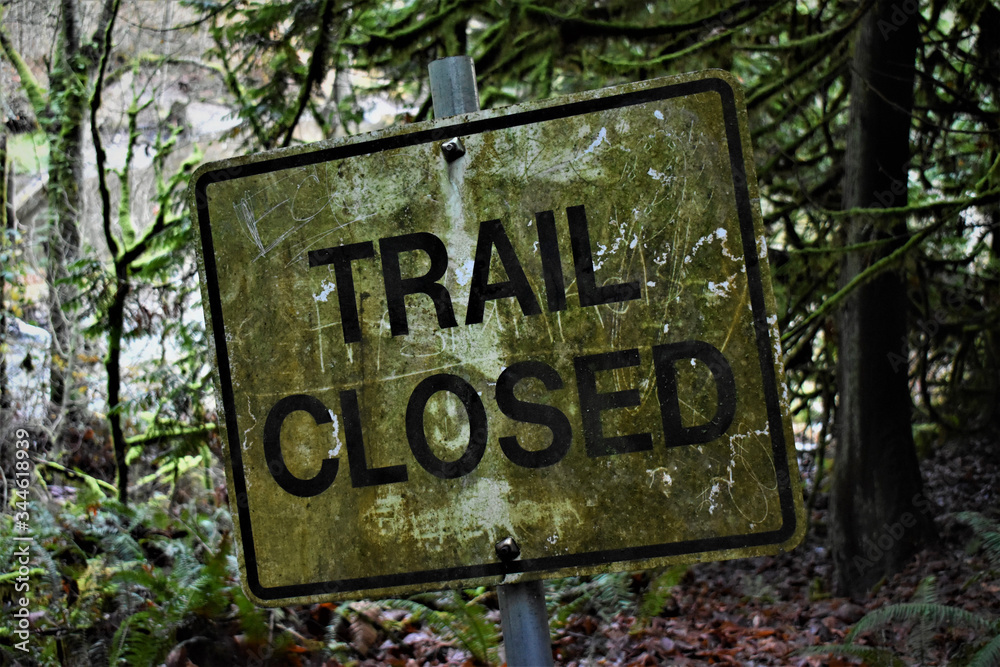 Trail Closed sign on a hiking trail. Covered in moss and dirt, kind of spooky. Trail Closed sign on a hiking trail. Covered in moss and dirt, kind of spooky.