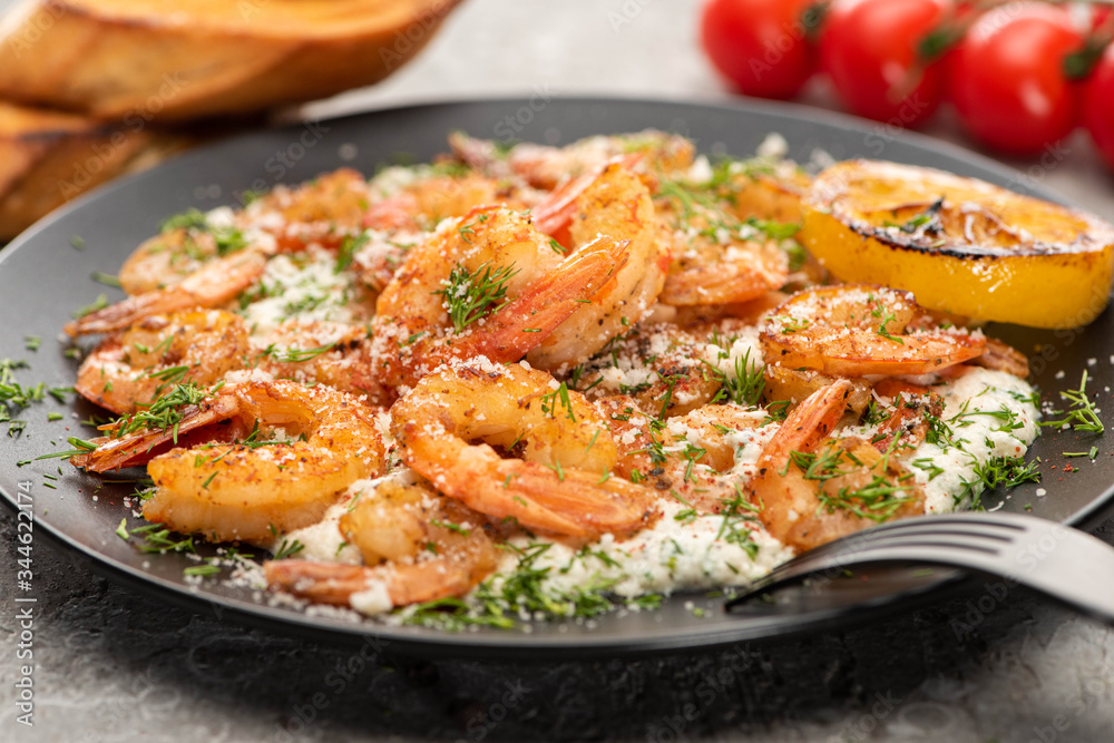 selective focus of fried shrimps in sauce with dill and lemon in black plate on grey concrete background selective focus of fried shrimps in sauce with dill and lemon in black plate on grey concrete background
