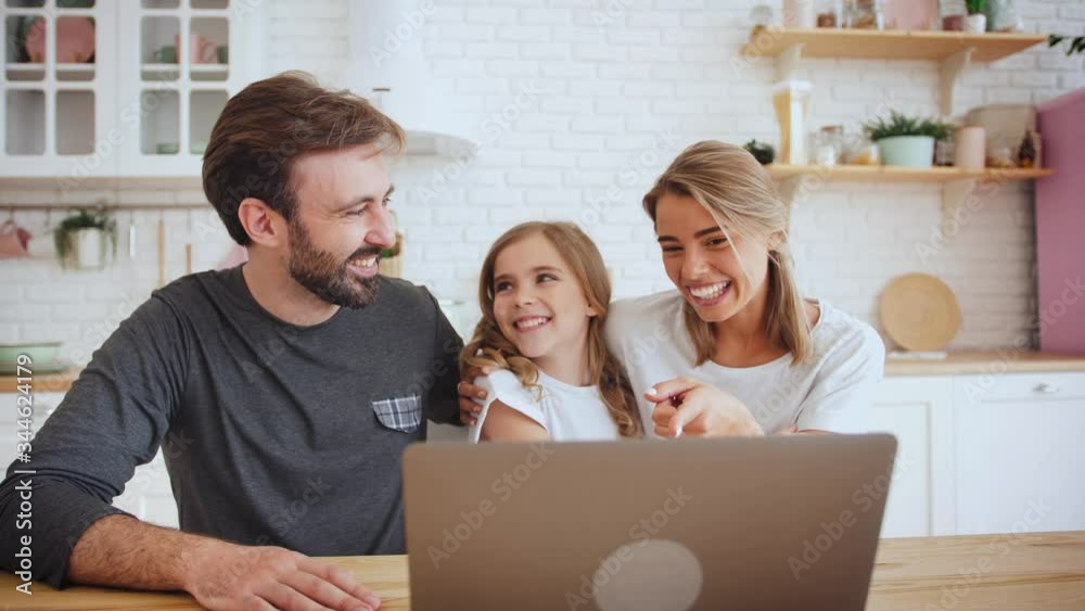 Portrait of happy positive family young using laptop computer for a video call in the kitchen and waving hands, slow motion Portrait of happy positive family young using laptop computer for a video call in the kitchen and waving hands, slow motion