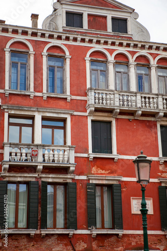 Close up. Traditional red facade of the italian vintage building with a chimney, wooden shutters, white marble balconies in the center of Venice, Veneto, Italy. European architecture.
