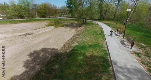 boy riding a blue Bicycle with side wheels along the path in the nature