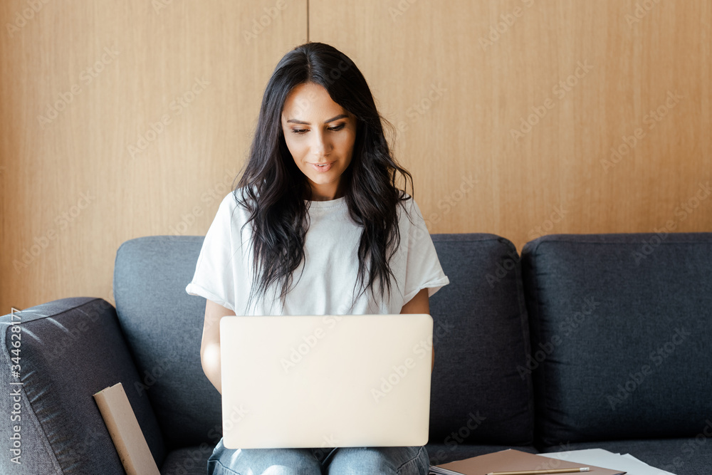 beautiful young woman working on laptop with business documents on sofa beautiful young woman working on laptop with business documents on sofa