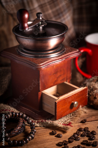 Old vintage manual coffee grinder with coffee beans on wooden background