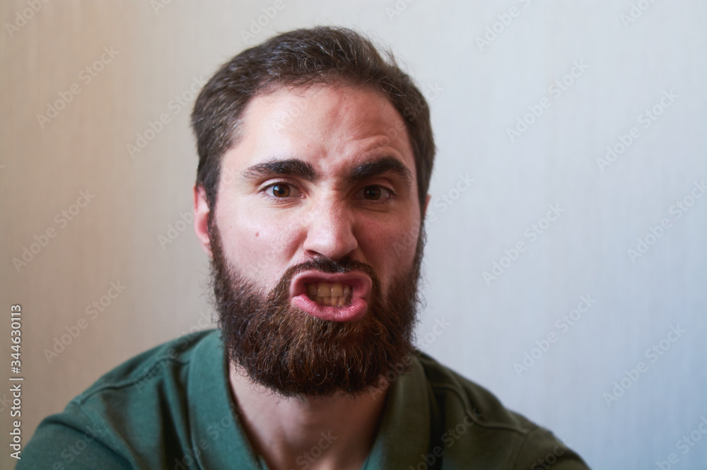 Portrait of young guy with dark beard with various emotions on his face in green shirt. Portrait of young guy with dark beard with various emotions on his face in green shirt.