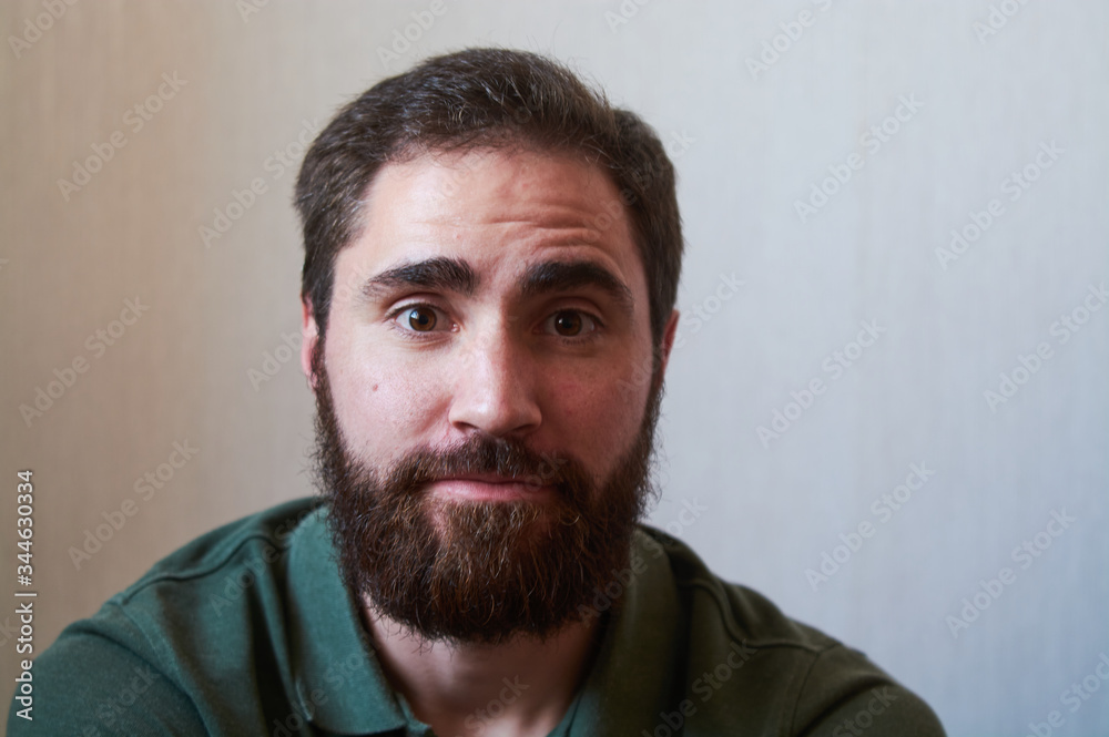 Portrait of young guy with dark beard with various emotions on his face in green shirt. Portrait of young guy with dark beard with various emotions on his face in green shirt.