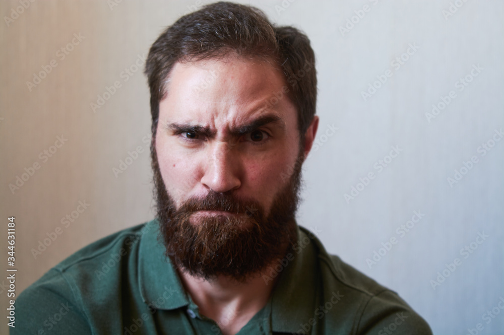 Portrait of young guy with dark beard with various emotions on his face in green shirt. Portrait of young guy with dark beard with various emotions on his face in green shirt.