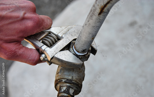  plumbing wrench in hand and old water tap