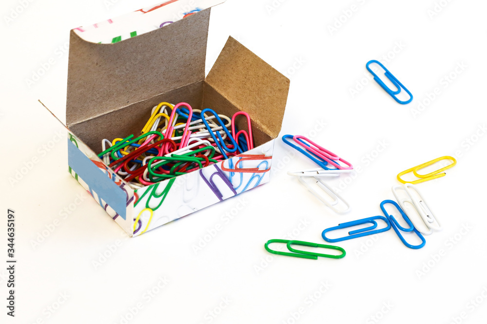 A bunch of colored clerical staples in a croarbka on a white background. Office accessories. Binding of documents and paper with the help of staples.