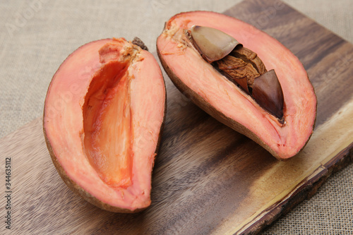 two half cut organic fresh Mamey Sapota (Pouteria sapota) or sweet plum on wooden board