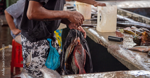 Unrecognizable creole man holding big tuna fish at the street market. Mahe island, Seychelles