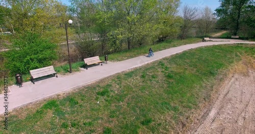 the boy was riding in the Park on a blue bike with side wheels