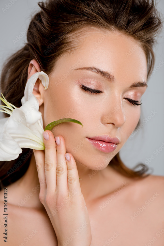 attractive woman with closed eyes holding white flower isolated on grey attractive woman with closed eyes holding white flower isolated on grey