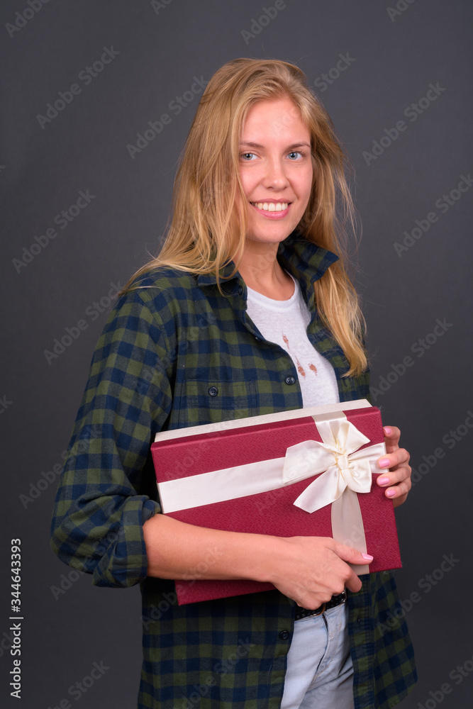 Portrait of happy young blond hipster woman holding gift box Portrait of happy young blond hipster woman holding gift box