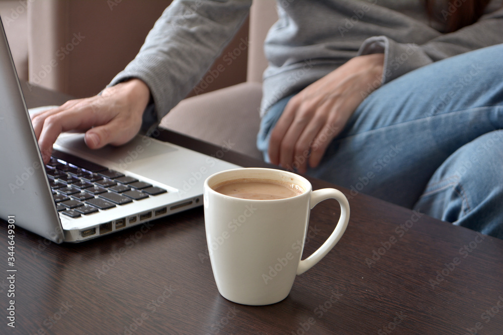 Online and remote work or home distance education concept. Close up of a young female freelancer working on a laptop from a home office Online and remote work or home distance education concept. Close up of a young female freelancer working on a laptop from a home office