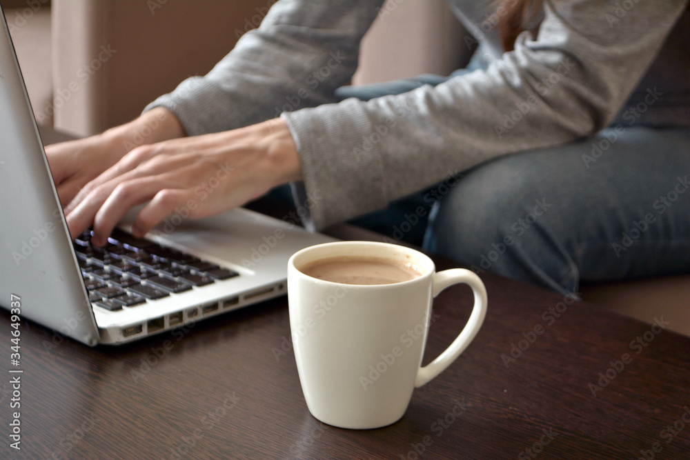 Online and remote work or home distance education concept. Close up of a young female freelancer working on a laptop from a home office Online and remote work or home distance education concept. Close up of a young female freelancer working on a laptop from a home office