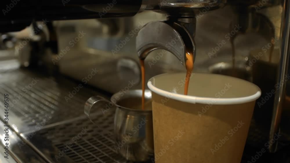 Coffee is poured into a paper cup. Coffee machine close-up Coffee is poured into a paper cup. Coffee machine close-up
