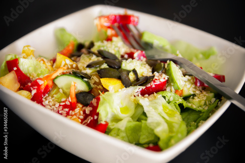 Vegetable Salad. Salad of tomato, cucumber, lettuce, sprinkled with sesame seeds. Salad in a white plate.