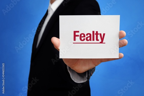 Fealty. Lawyer in a suit holds card at the camera. The term Fealty is in the sign. Concept for law, justice, judgement