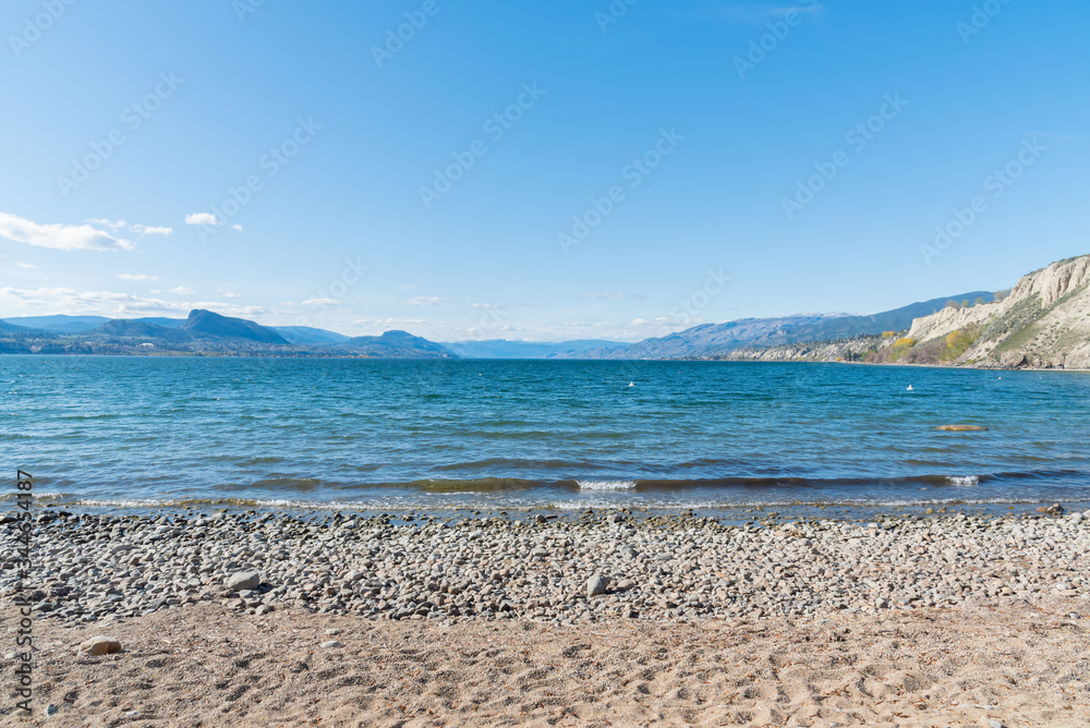 View of Okanagan Lake, beach, and blue sky on sunny afternoon