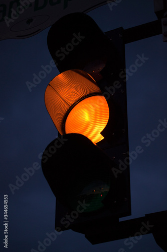 Yellow traffic light against the sky at twilight. Yellow light is on at a traffic light pole in the evening.