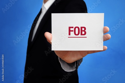FOB. Lawyer in a suit holds card at the camera. The term FOB is in the sign. Concept for law, justice, judgement