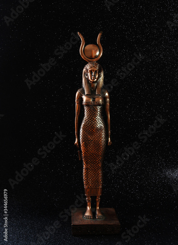 The Egyptian goddess ISIS on a black background. A bronze Egyptian goddess with a circle on her head. photo