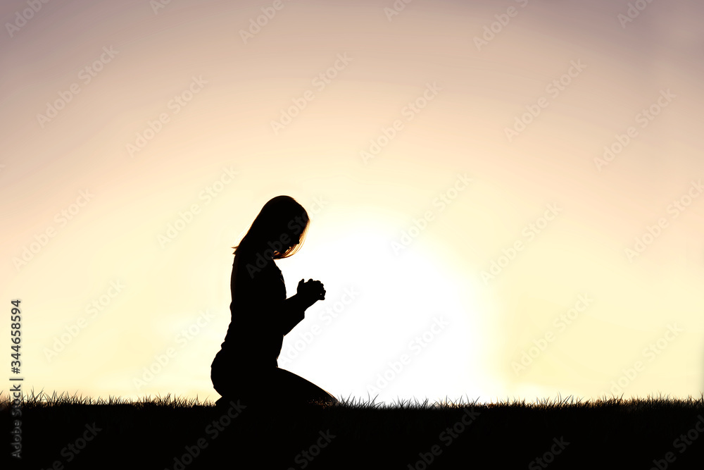 Young Christin Woman Praying Outside at Sunset on a Summer Day