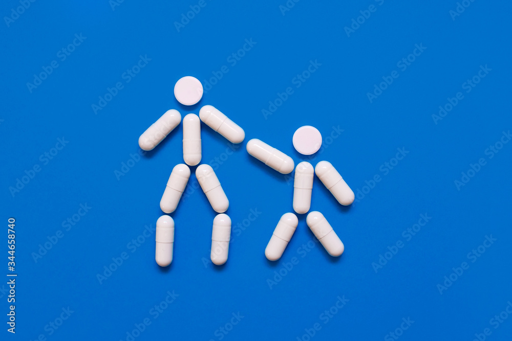 The shape of two little men from tablets on a blue background, the concept of treatment and protection against disease The shape of two little men from tablets on a blue background, the concept of treatment and protection against disease