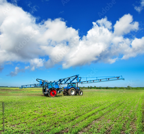 new blue tractor in field work with trailed sprayer, winter crop fertilizers,...