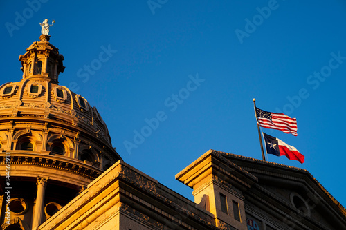 The American and Texas flags wave in the wind at sunset on the Texas Capitol building photo