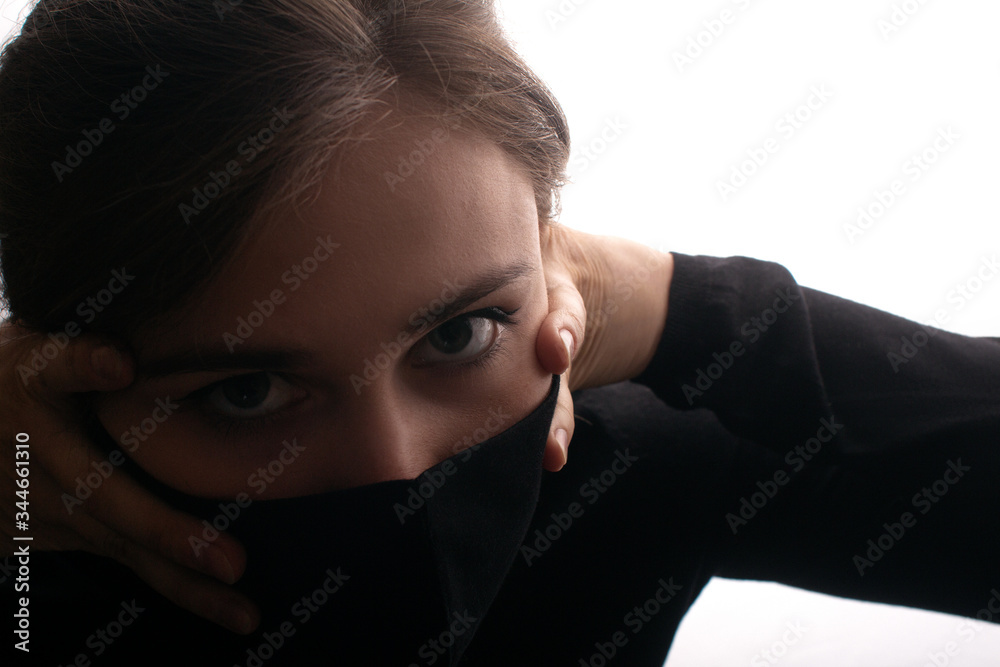 portrait face of young beautiful woman in a black stylish mask with hands clutching neck, lifestyle 2020 under quarantine and epidemic smothers a person, concept of danger portrait face of young beautiful woman in a black stylish mask with hands clutching neck, lifestyle 2020 under quarantine and epidemic smothers a person, concept of danger