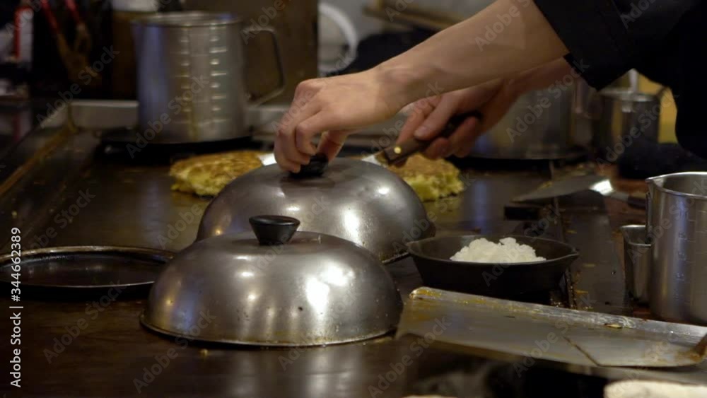 Slow motion of Pan-fried guotie. A professional chef cooking deep fried dumplings on iron griddle. Japanese delicious food. Man cooks in a restaurant, he works in a traditional kitchen-Dan Slow motion of Pan-fried guotie. A professional chef cooking deep fried dumplings on iron griddle. Japanese delicious food. Man cooks in a restaurant, he works in a traditional kitchen-Dan