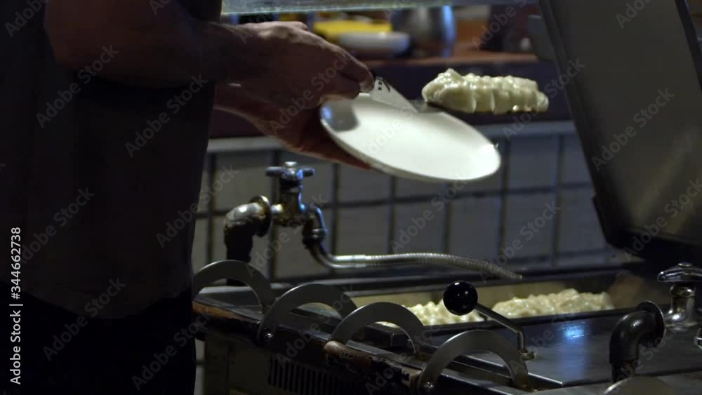Slow motion of Pan-fried guotie. A professional chef cooking deep fried dumplings on iron griddle. Japanese delicious food. Man cooks in a restaurant, he works in a traditional kitchen-Dan