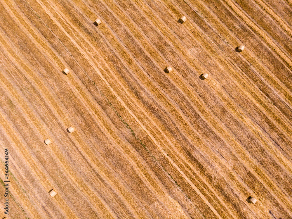 Aerial view of harvested wheat field. Haystacks lay upon the agricultural field. Aerial view of harvested wheat field. Haystacks lay upon the agricultural field.