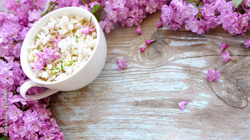 Cup of tea with lilac flowers on wooden background. Spring time. Vase with lilac. Copy space for text. The concept of holidays and good morning wishes. 