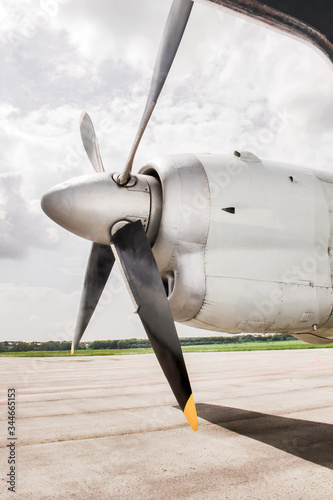 Propeller of an aircraft close-up. Airplane turboprop engine with wing and with 4 blade and with propeller, parts of aircraft fuselage on the cloudy sky and nature background. plane landed