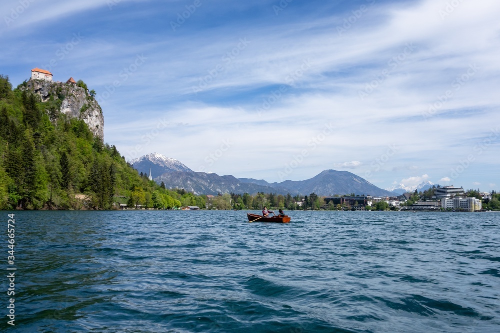 Tourists rowing on a boat on Bled Lake with the Bled Castle in Slovenia, Europe in the background