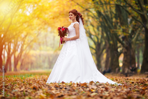 Young bride in wedding dress walking in a park. White luxury gown fashion for woman. The bride walks in the park.