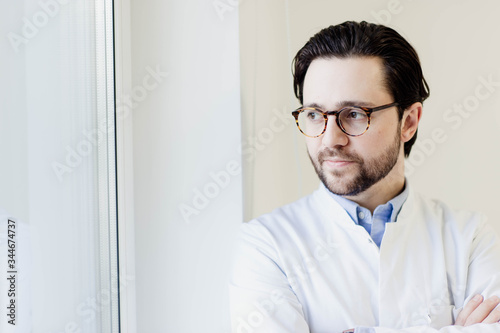 Portrait of handsome doctor brunet man in white coat in medical office with glasses. brutal and handsome man.