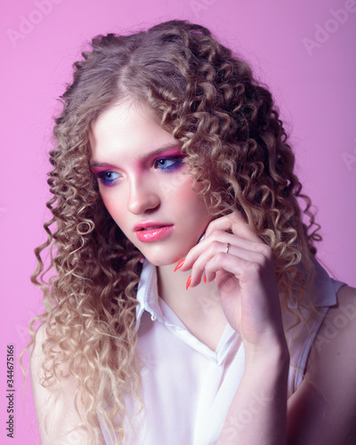 Portrait of a curly cheerful girl with professional make-up and retouching in the studio